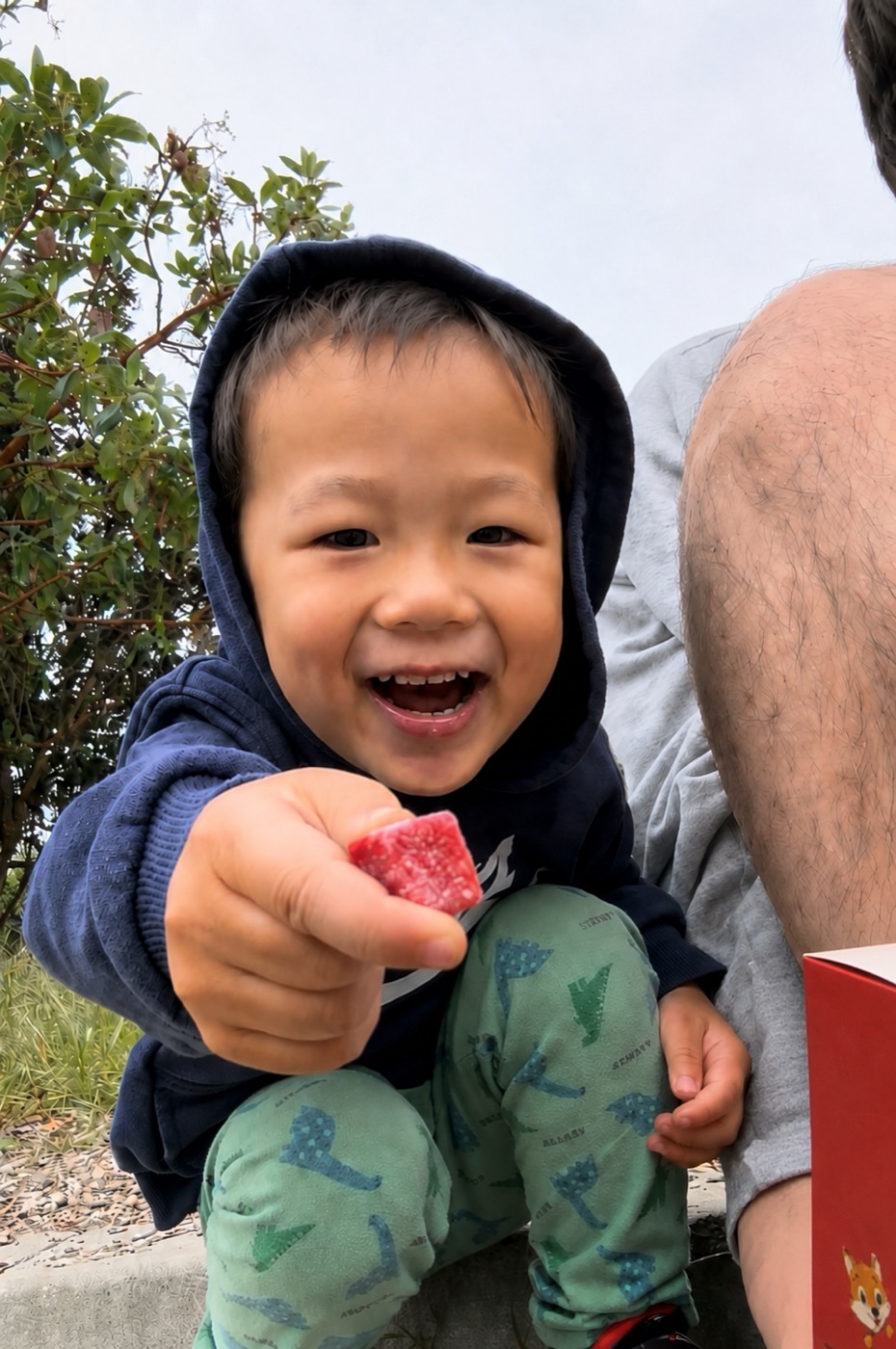 My son grinning, holding a Melons gummy with the pouch beside him